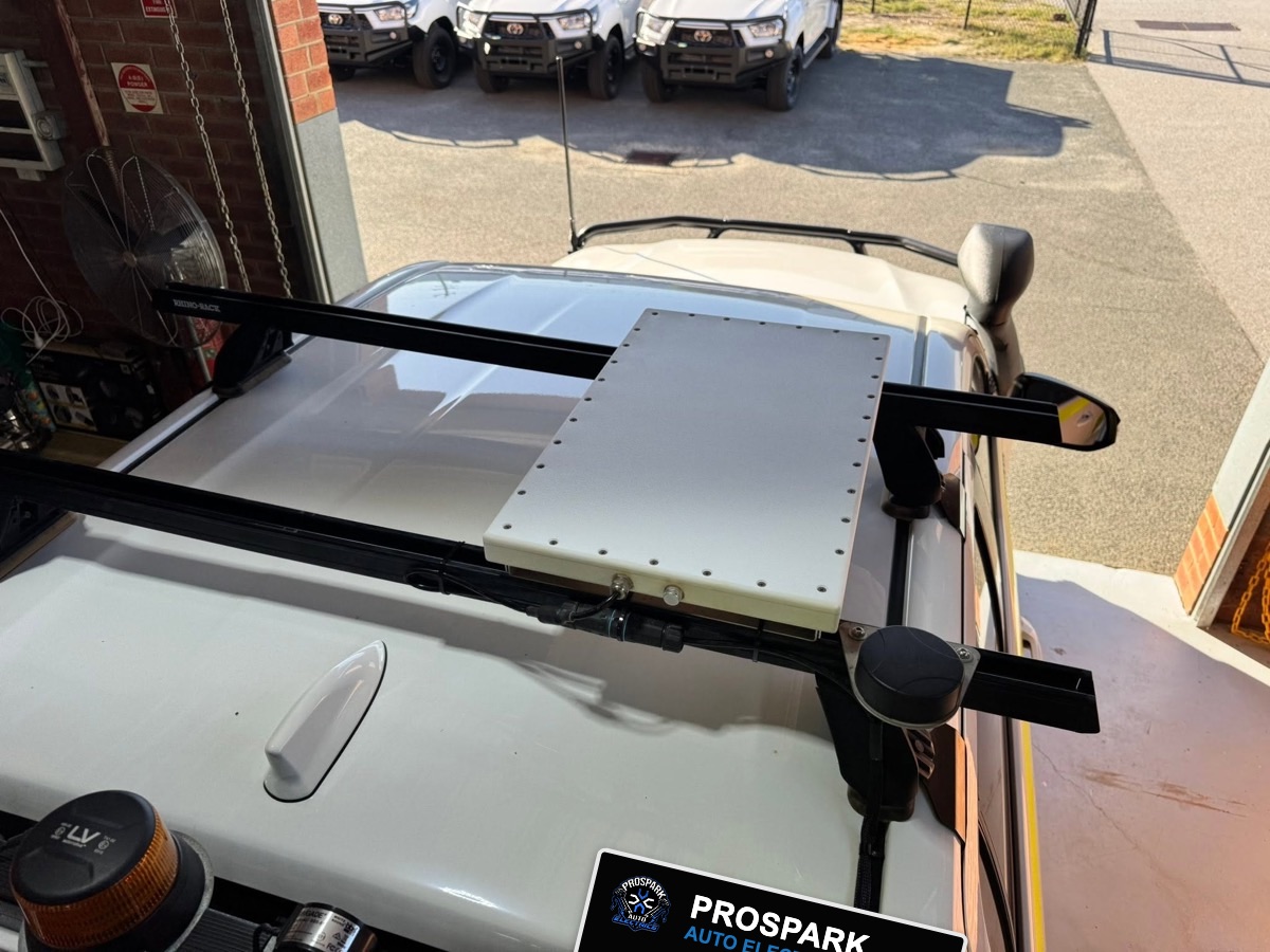 White roof panel and puck antenna mounted on Rhino-Rack roof bars on a work ute, with a UHF antenna at the front