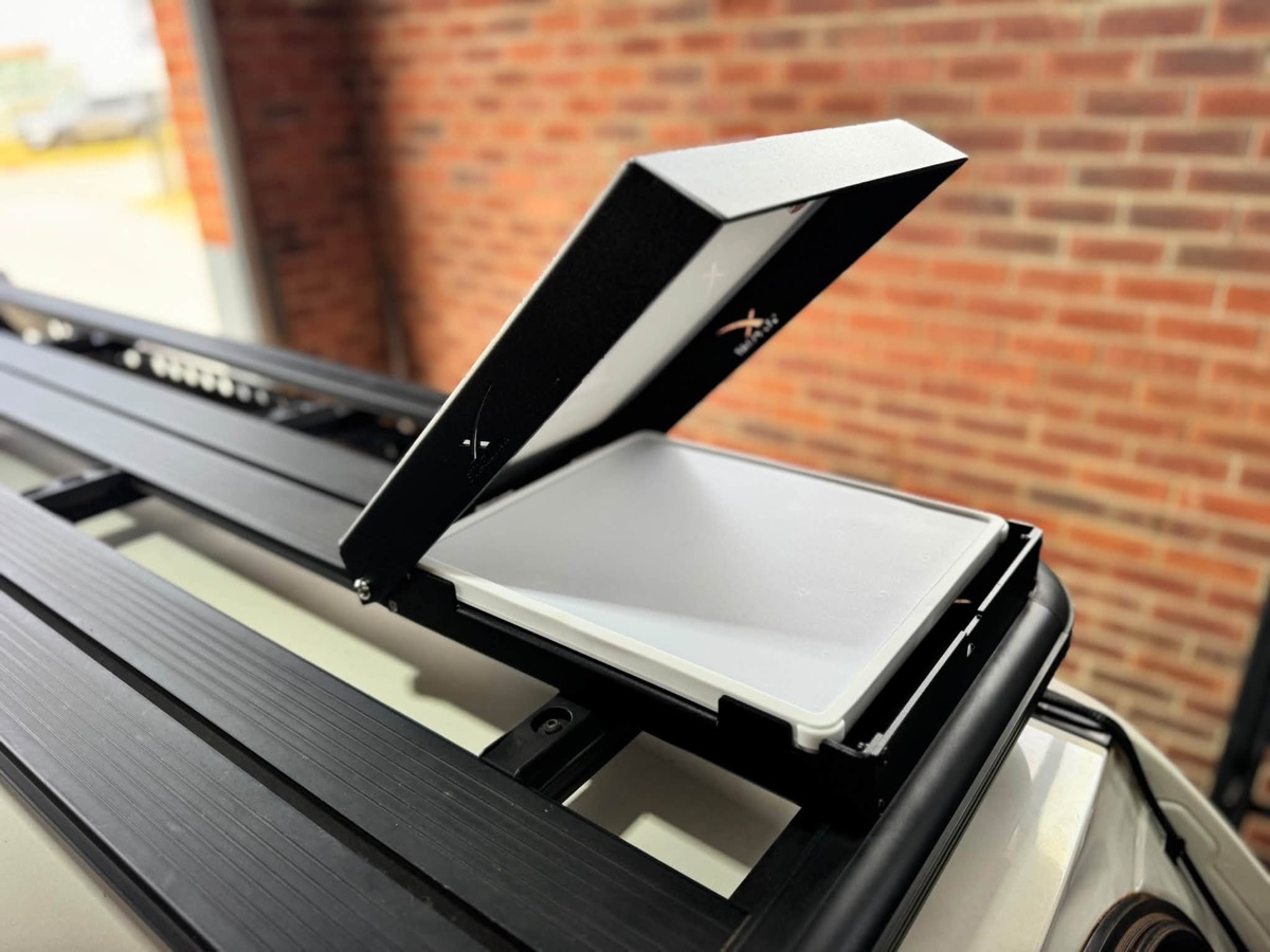 Starlink in a low-profile roof-rack mount with its hinged cover open