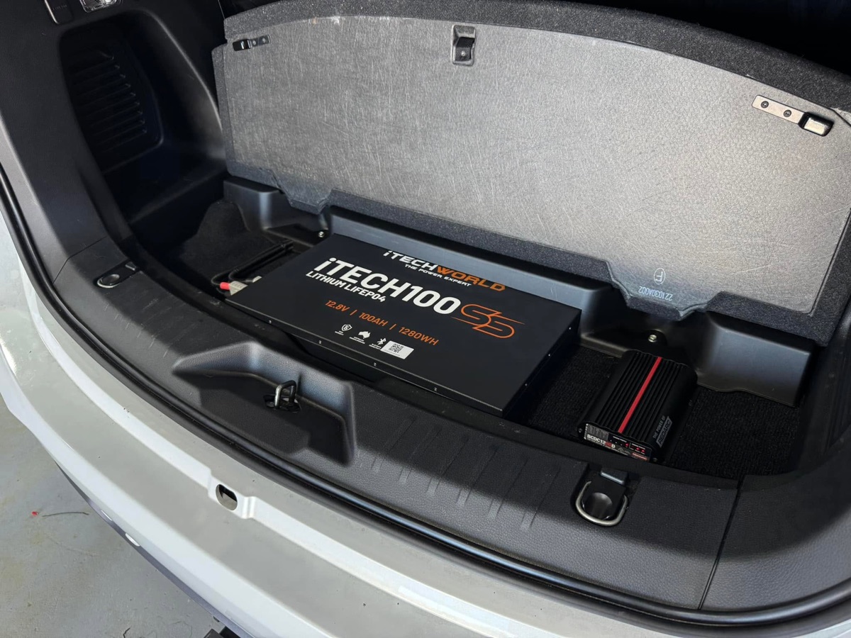 iTech100 lithium battery and REDARC BCDC charger in the rear storage well of a silver SUV