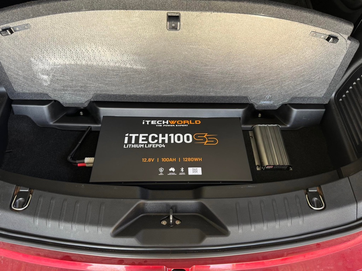 iTech100 lithium battery and REDARC BCDC charger neatly fitted in the rear storage well of a red SUV